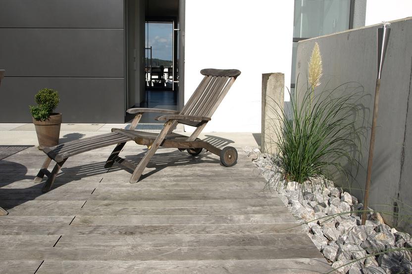 Individuelle Terrasse mit Holzboden und Holzliege vor Terrassentür