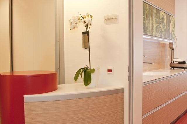 Individuelle Büroeinrichtung mit Blick auf Empfangstresen aus Holz neben rotem Möbelelement