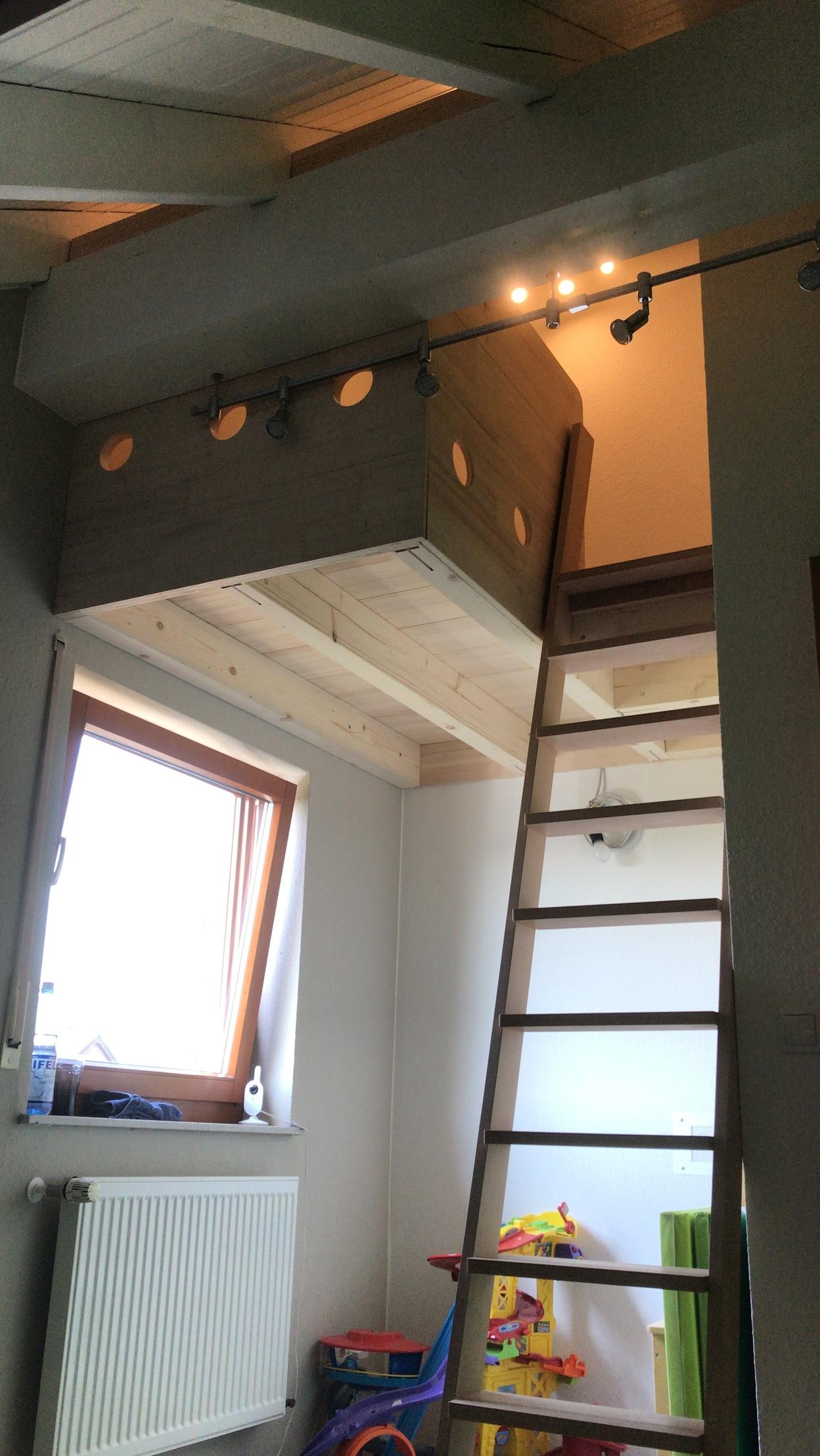 Ein Zimmer mit einem Hochbett aus hellem Holz, Leiter, Spielzeug und einem Fenster.