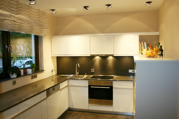 Elegante Küche mit Edelstahl-Arbeitsplatten, weißen Schränken und einer Fensteraussicht.