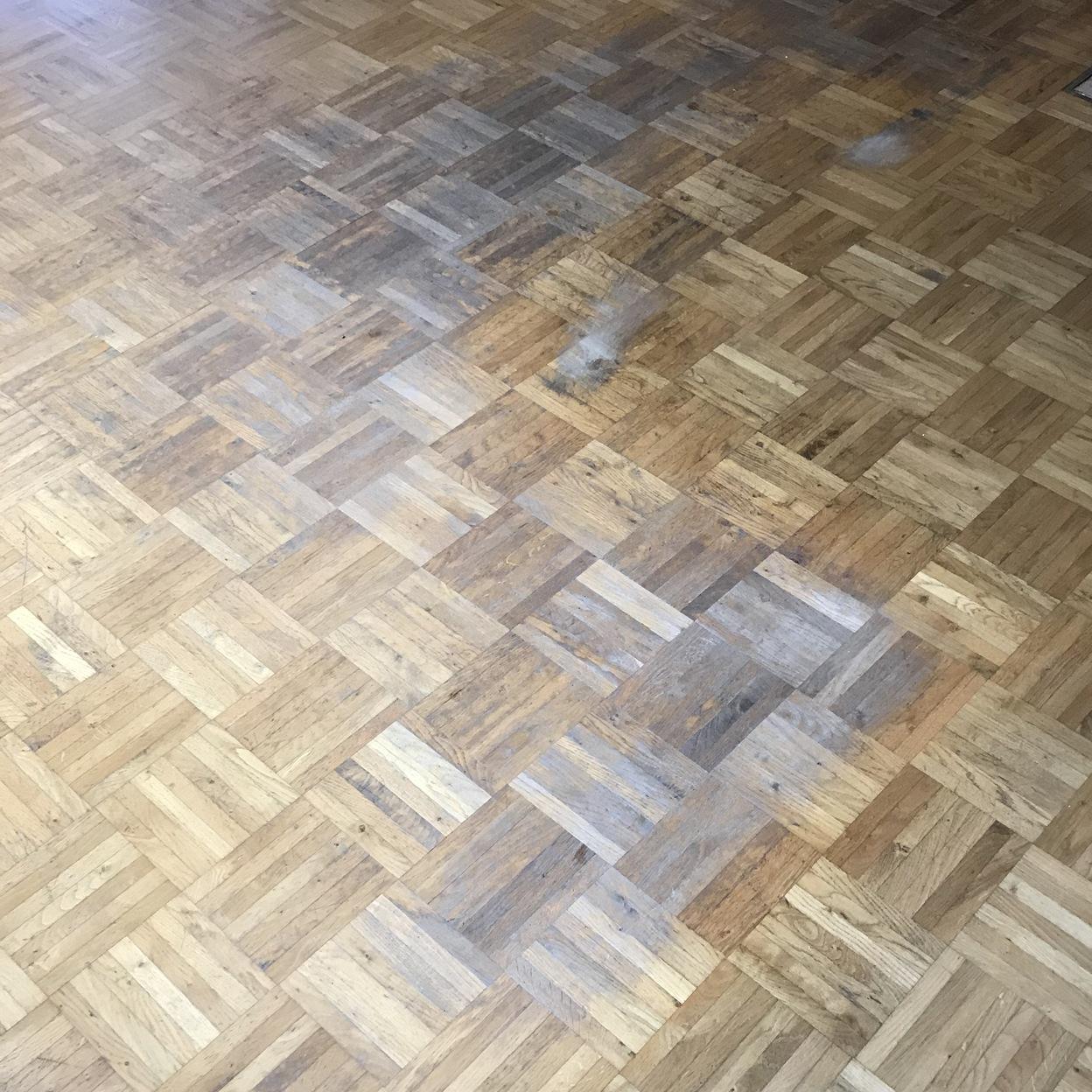 Ein abgenutzter Parkettboden mit deutlichen Gebrauchsspuren und Verf&auml;rbungen. Der Boden zeigt Bereiche, die geschliffen oder restauriert werden m&uuml;ssen, um den urspr&uuml;nglichen Glanz wiederherzustellen.