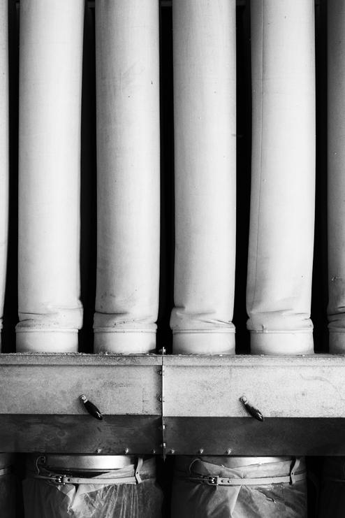 Symmetrische Anordnung von bearbeiteten Holzsäulen, die auf einem Regal über Eimern stehen.