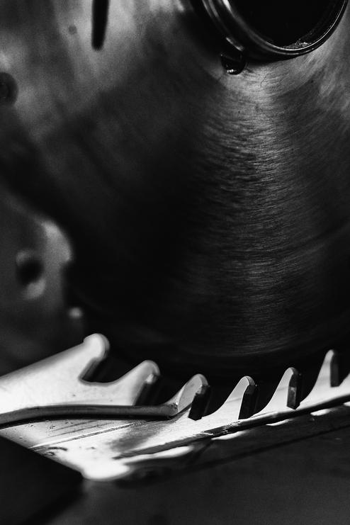 Detailansicht einer stillstehenden Kreissäge mit scharfen Zähnen und metallischer Oberfläche.