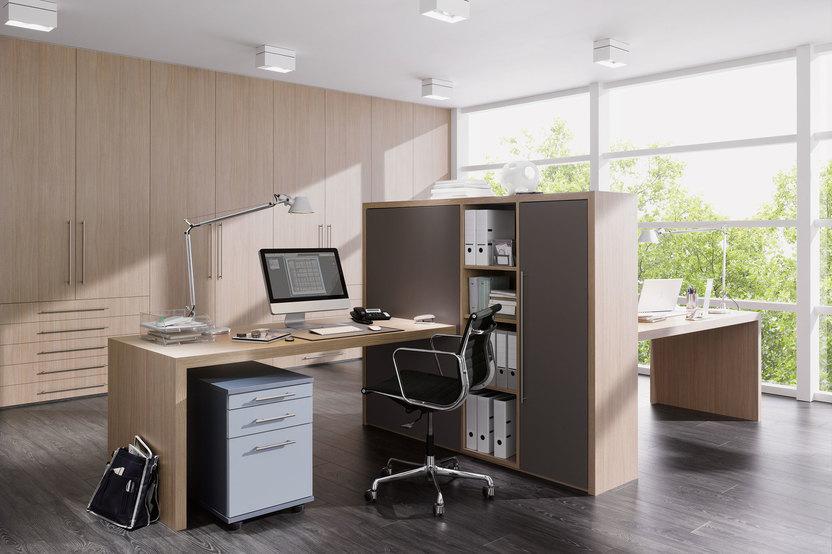 Impression von freistehenden Büromöbeln in L-Form mit hellem Einbauschrank im Hintergrund