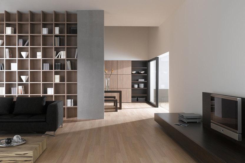 Offene Wohnraumimpression mit Einbauregal für Bücher und Dekoration in Trennwand mit hellem Holzboden