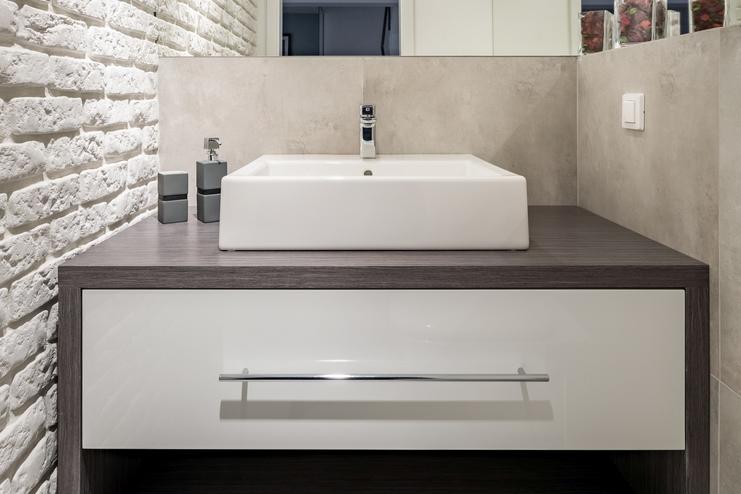 Nischenlösung für Waschtisch im Gäste-WC mit weißer Schublade an Betonwand