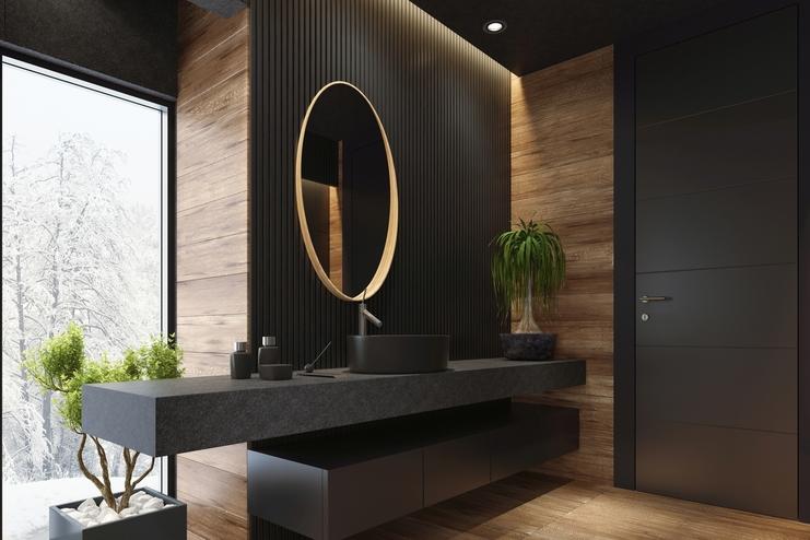 Lichtdurchflutetes Badezimmer mit dunkler schwarzer Waschtischarbeitsplatte, die über die Wand hinausragt und hängendem Unterschrank, runder Spiegel, Wandkontrast in Holz.