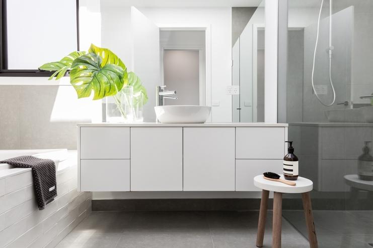 Weißer Waschtischunterschrank ohne Griffe mit Schubladen und Türen in heller Badgestaltung